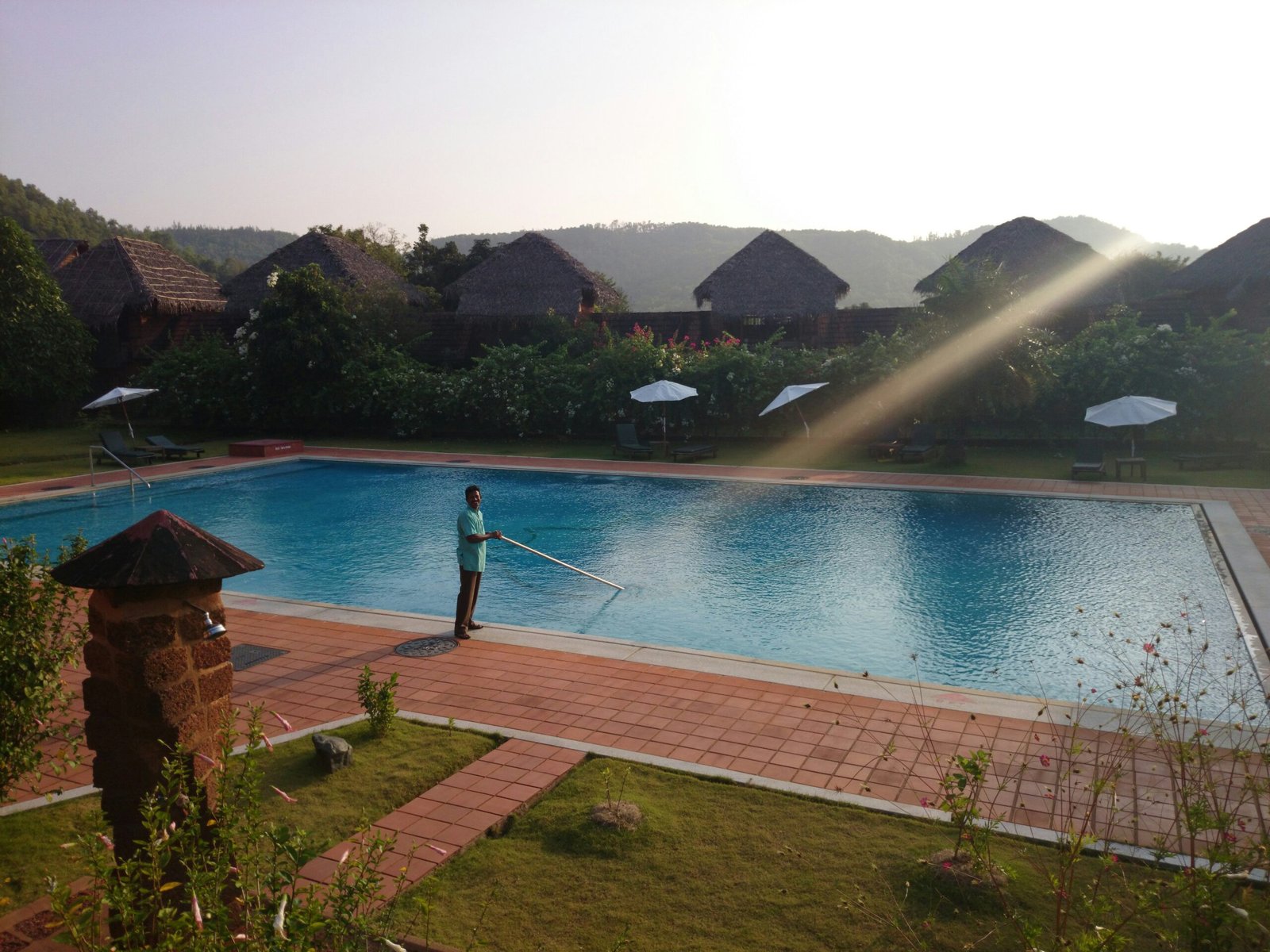 man cleaning a large pool in backyard