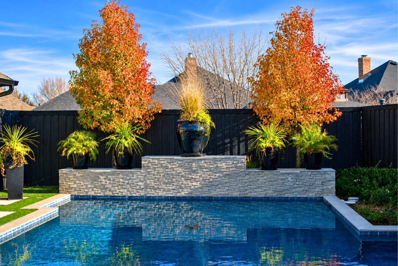 Luxury backyard swimming pool with decorative stone wall, premium landscaping, and modern outdoor living in Amarillo, Texa