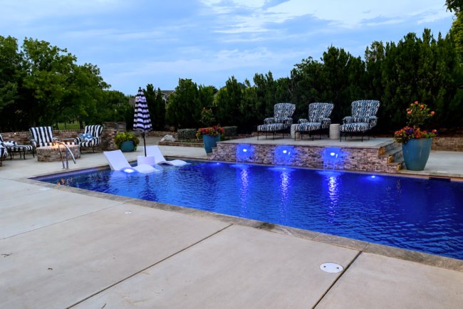 Luxury custom inground swimming pool with LED lighting, tanning ledge, sheer descent waterfalls, and elevated lounge area in Amarillo, Texas. Luxury Pool with Water Features in Amarillo, TX